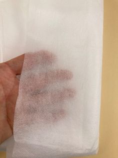 a hand holding a white cloth with red stains on it