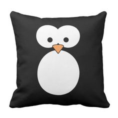 a black and white pillow with a penguin face on the front, it has an orange beak