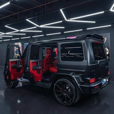 a black and red jeep parked in a parking garage next to another vehicle with its doors open