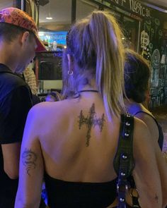 a man and woman standing next to each other in front of a bar with tattoos on their back