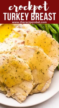 a white plate topped with meat covered in gravy next to asparagus