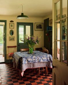 a dining room table with a blue and white checkered table cloth on it, in front of a green door