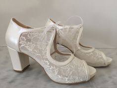 a pair of women's white shoes with lace on the top and heel straps