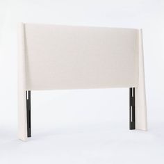 an upholstered headboard with black legs and a white sheet over the top