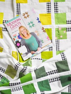 a book sitting on top of a quilt next to a white and green bed spread