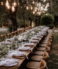 a long table is set up with plates and place settings for an outdoor dinner party