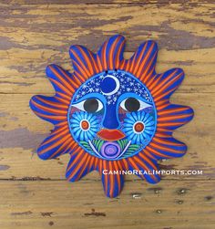 a blue and orange sun face hanging on a wooden wall