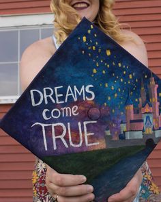 a woman holding up a graduation cap that says dreams come true