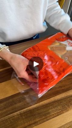 a person holding a plastic bag on top of a wooden table