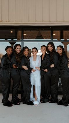 a group of women standing next to each other in front of a glass door with their arms around one another