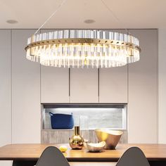 a modern chandelier hangs over a dining room table with chairs and bowls on it