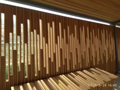 a wooden bench sitting next to a window covered in slatted bamboo blinds on the side of a building