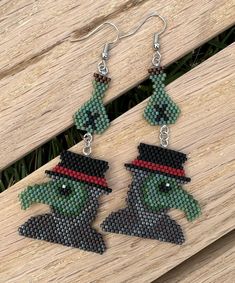 a pair of beaded earrings with an image of a frog wearing a top hat