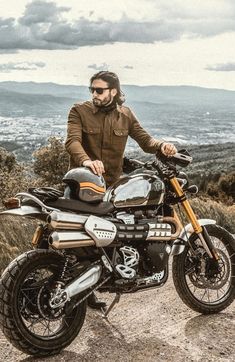 a man standing next to a motorcycle on top of a hill