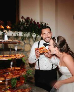 a bride and groom sharing a slice of pizza