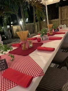 a table set up with red and white checkered cloths, napkins and vases