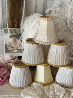 three lamps are stacked on top of each other in front of some pink flowers and lace