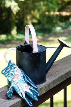 a watering can and gardening gloves on a wooden bench