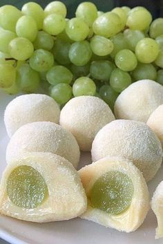 some grapes are sitting on a plate next to small pastries