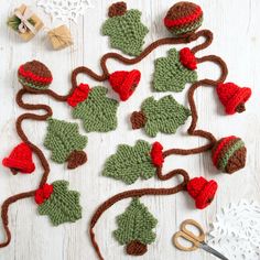 crocheted christmas decorations are arranged on a white wooden surface with scissors and yarn