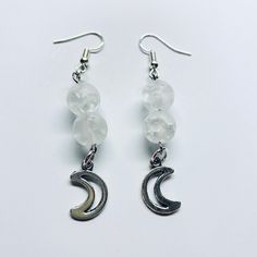 These beautiful dangle moon themed earrings are handmade with moon themed stone beads, moon charms, and silver fishhook ear wire.  They are approximately 2 inches long and are relatively lightweight. Every pair of earrings also comes with a complimentary organza bag and clear earring backs that stay on all day! These unique statement earrings have a super cool celestial vibe and go well with so many outfits! Get yours today for yourself or as a gift for a friend or family member! Celestial White Sterling Silver Earrings, White Sterling Silver Celestial Earrings, Celestial Moon Charm Crystal Earrings, Moonstone Moon Charm Drop Earrings, Nickel-free Moonstone Moon Earrings, Nickel-free Moonstone Moon-shaped Earrings, White Moon Phase Dangle Jewelry, Crystal Moon Earrings With Moon Charm As Gift, Moon Shaped Crystal Earrings With Moon Charm As Gift