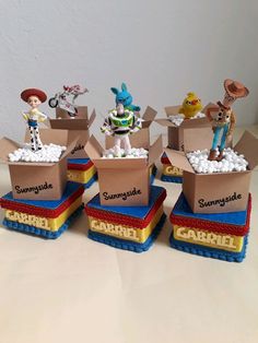 three cardboard boxes with toy figures in them sitting on a table next to each other