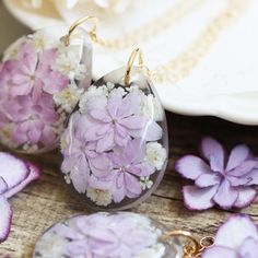 purple and white flowers in glass tear shaped pendants