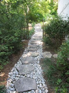 there is a stone path in the middle of this yard that leads to a house