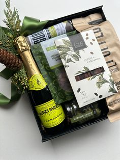 an open gift box containing wine, condiments, and other items on a white surface