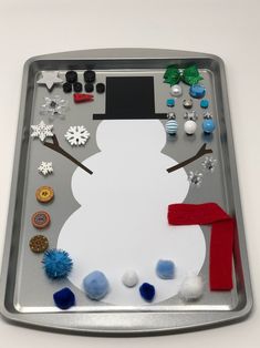 a metal tray with a snowman made out of buttons and other things on it