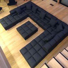 a large black couch sitting on top of a hard wood floor next to a chair