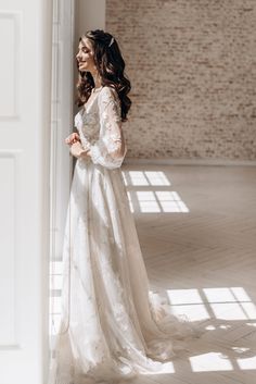 a woman in a white wedding dress leaning against a wall