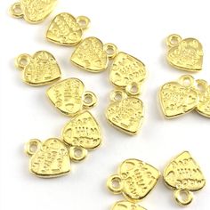 heart shaped gold jewelry charms with the words made with love on them, on a hand to show scale Gold Heart Charm Necklace Nickel Free, Gold Heart-shaped Nickel-free Charm Necklace, Gold Heart Charms For Jewelry Making, Gold Heart Charm Pendant, Gold Charm Necklaces For Birthday, Gold Heart Beads Jewelry For Birthday, Gold Double Heart Charm Necklace With Beads, Gold Round Charm Necklace With Heart Charm, Valentine's Day Heart-shaped Dangling Charms