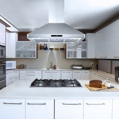 a kitchen with white cabinets and stainless steel range hood over the stove, oven and microwave