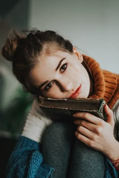 a woman is sitting on the floor with her book in her lap and looking at the camera