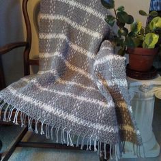 a chair with a blanket on it next to a potted plant