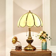 a table with a lamp on top of it next to a vase filled with flowers