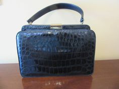 "We just received a large box full of mostly vintage bags and will be listing them slowly for sale. In this listing we are offering a Vintage 1950 Lucille DeParis Black Alligator Kelley Bag. The bag features a textured alligator design all over the bag with brass closure, handle rings etc. A single handle is found at the top of the bag. Closes with a snap on the front. The photos don't show it closed well but it does close nice and tight. The snap closure on the top has a brushed brass design at Vintage Crocodile Pattern Evening Bag, Vintage Evening Bags With Crocodile Pattern, Vintage Travel Bags With Crocodile Pattern, Vintage Crocodile Pattern Travel Bag, Retro Rectangular Bag With Crocodile Pattern, Black Rectangular Bag For Vintage Fashion, Black Alligator, Hanging Christmas Tree, Engraved Sign