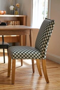 a black and white checkered chair sitting on top of a wooden floor next to a table