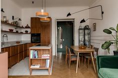 an open kitchen and dining room area with wooden flooring, green couches, white walls