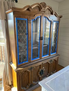 an old wooden china cabinet with blue glass doors