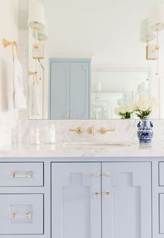 a blue and white bathroom with gold hardware on the cabinet doors, marble counter top