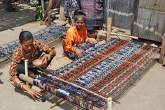 two women sitting on the ground weaving fabric