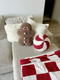 two gingerbread cookies sitting on top of a couch next to a candy cane pillow