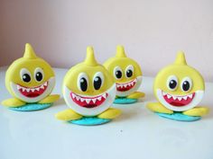 three yellow toys with big eyes and teeth on top of a white table next to each other