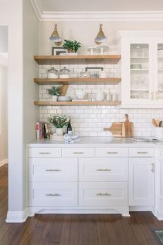 a white kitchen with open shelving and wooden flooring on the walls, along with shelves filled with pots and pans