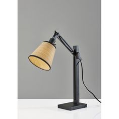 a black table lamp with a wooden shade on the base and a gray background behind it