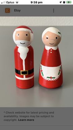 two wooden santa claus dolls sitting next to each other