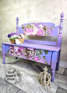 a bench with flowers painted on it next to a basket of flowers and a figurine