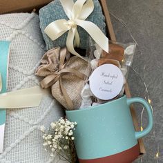 a blue coffee mug sitting on top of a bed next to a box of cookies